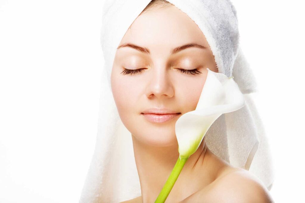 woman with peaceful expression holding a lily next to her face