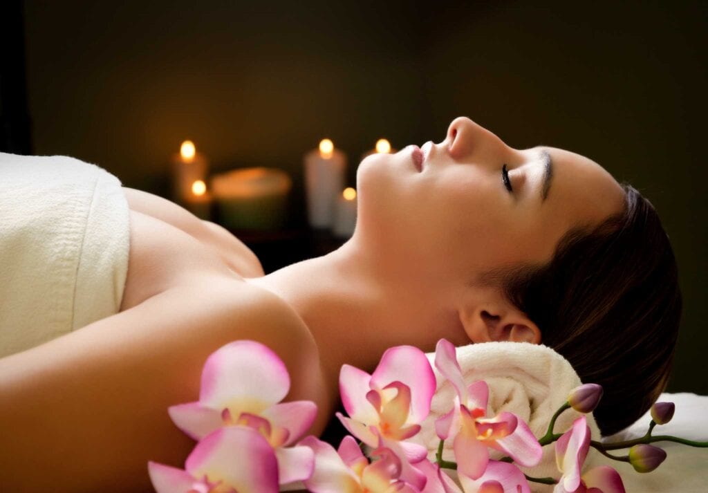 woman laying down for a massage next to flowers