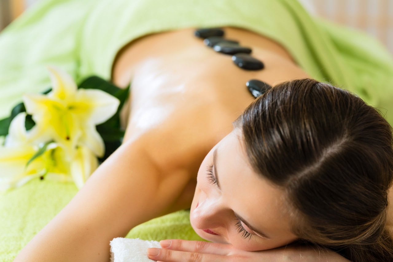 woman laying on her stomach with hot stones on her back